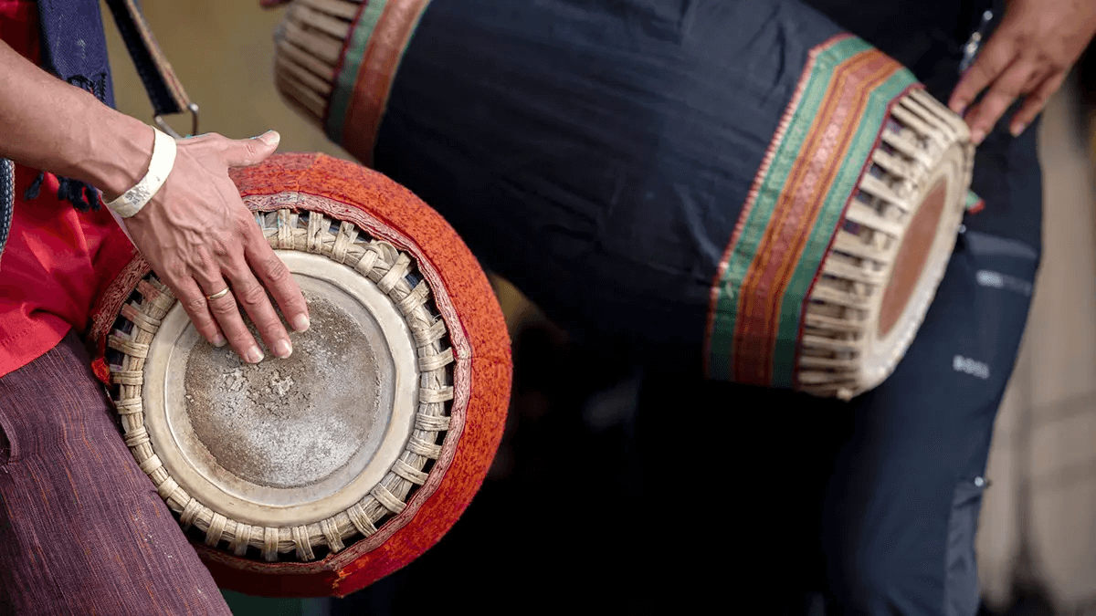 Hands playing a traditional drum during kirtan